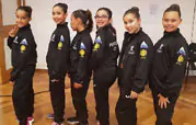 Foto sobre um grupo de meninas com fato de treino preto, a mostrar o logo da Ilhapeixe.