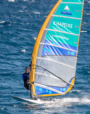 Foto sobre o atleta João Rodrigues a praticar windsurf, com o logo Ilhapeixe estampado na vela.
