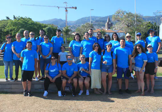 Um grupo de colaboradores da Ilhapeixe com t-shirts azuis, em frente à paisagem do Funchal.