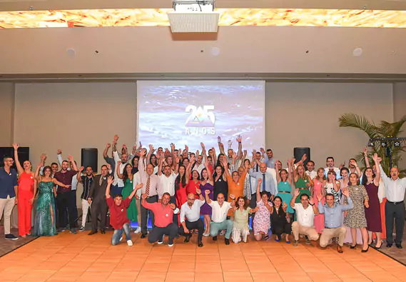 Colaboradores da Ilhapeixe com os braços no ar, em frente a um ecrã com o logo dos 25 anos da Ilhapeixe.