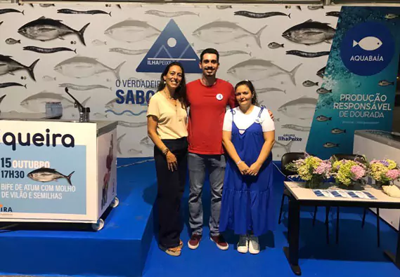 Two women and a man smiling on the center of ilhapeixe's booth.